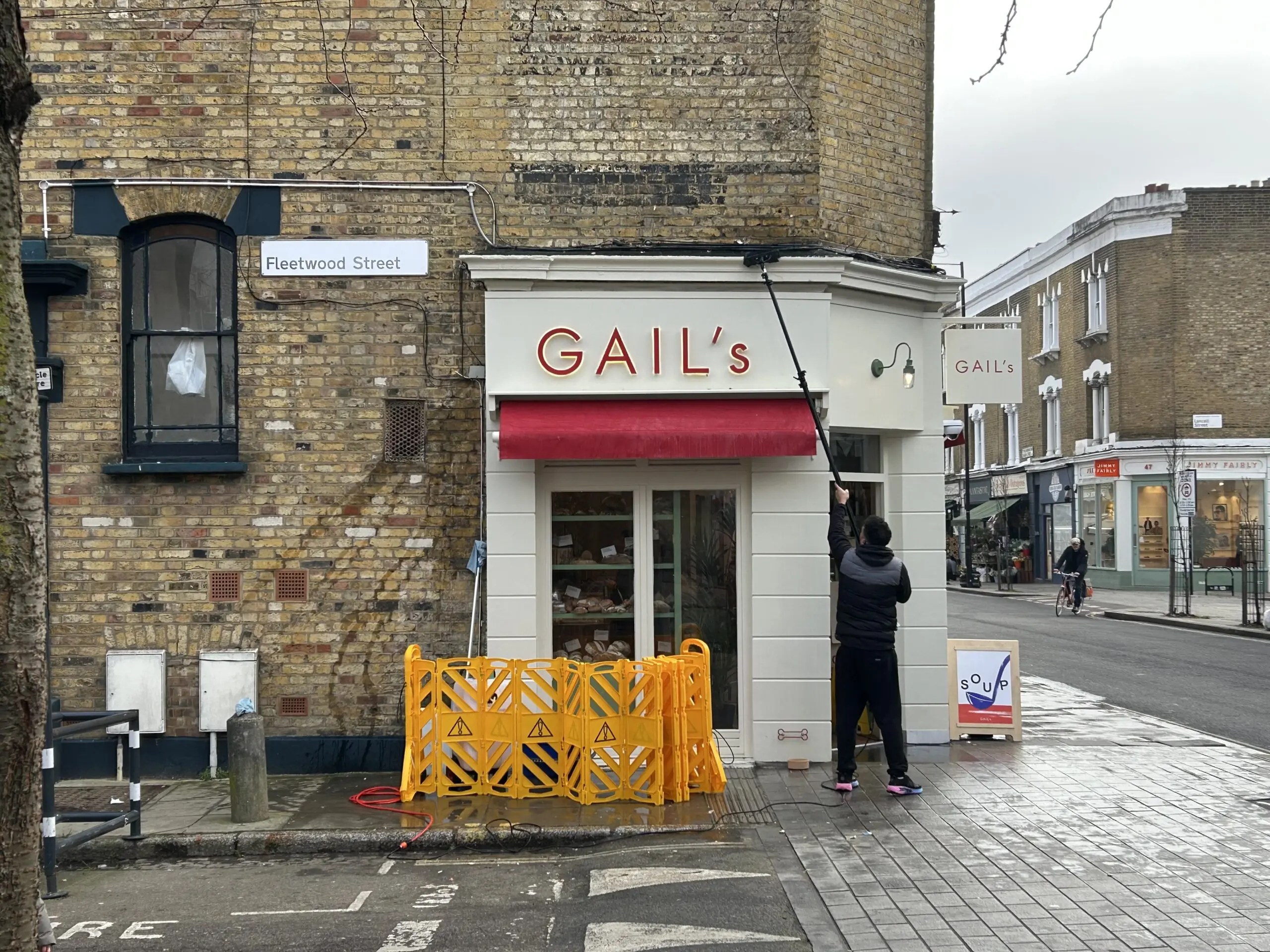 A man cleaning up eggs on Gail's Bakery window in Stoke Newington