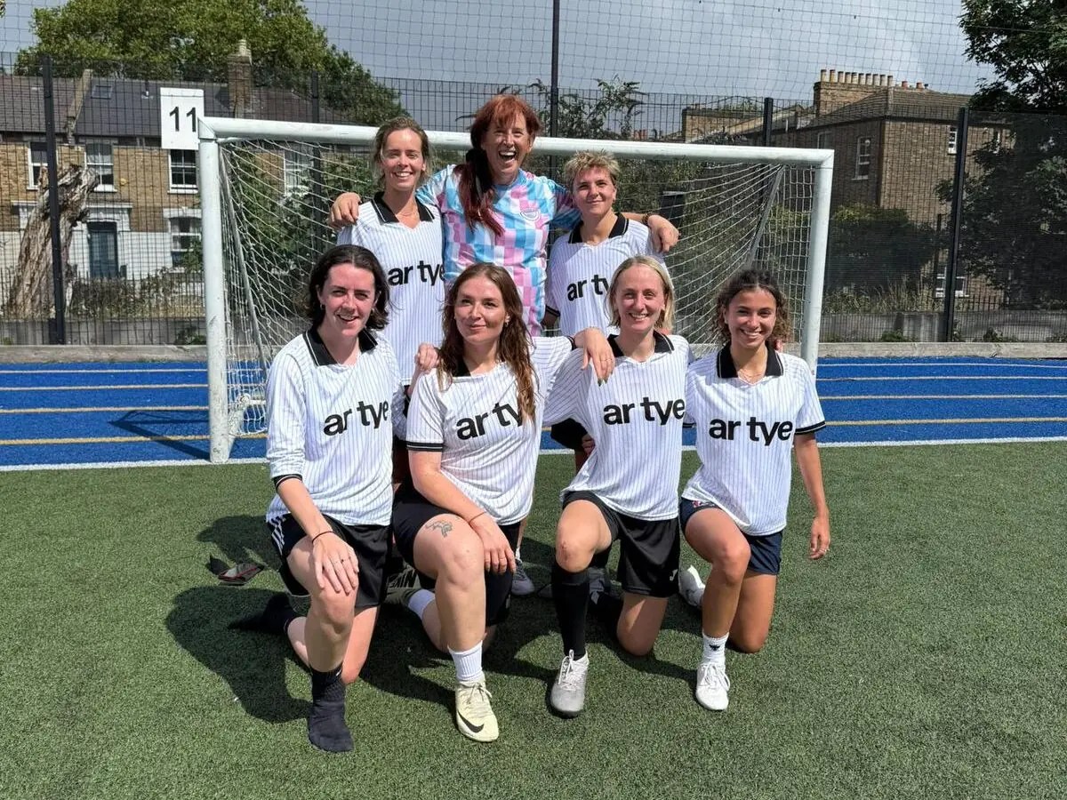 Photo of Sonder FC team, smiling in front of a goalpost on a pitch