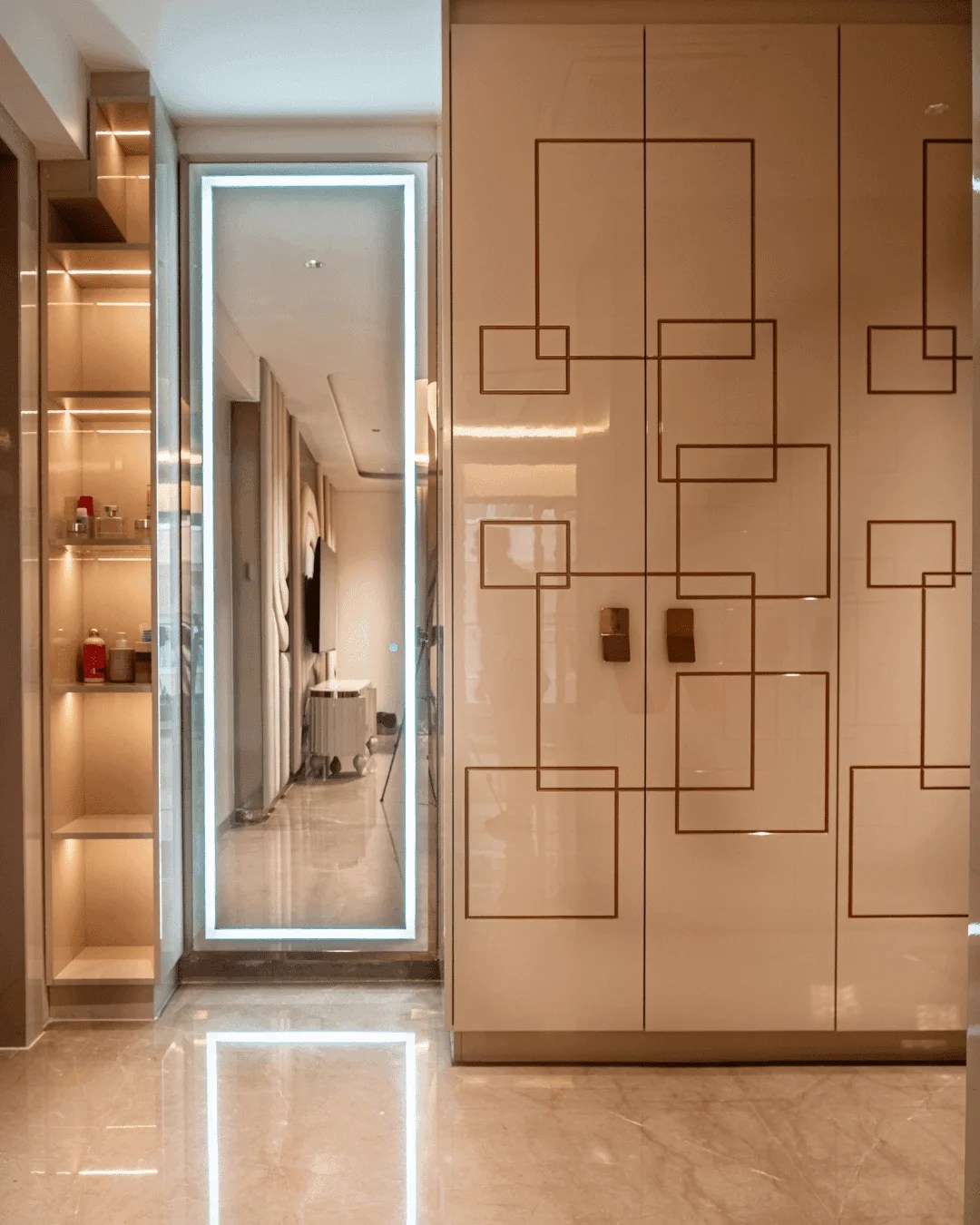 A luxury private walk-in closet featuring floor-to-ceiling cabinetry with a high-gloss lacquered finish and delicate gold geometric linear inlays. This sophisticated space includes integrated LED shelving and a backlit vanity mirror, set on polished marble floors