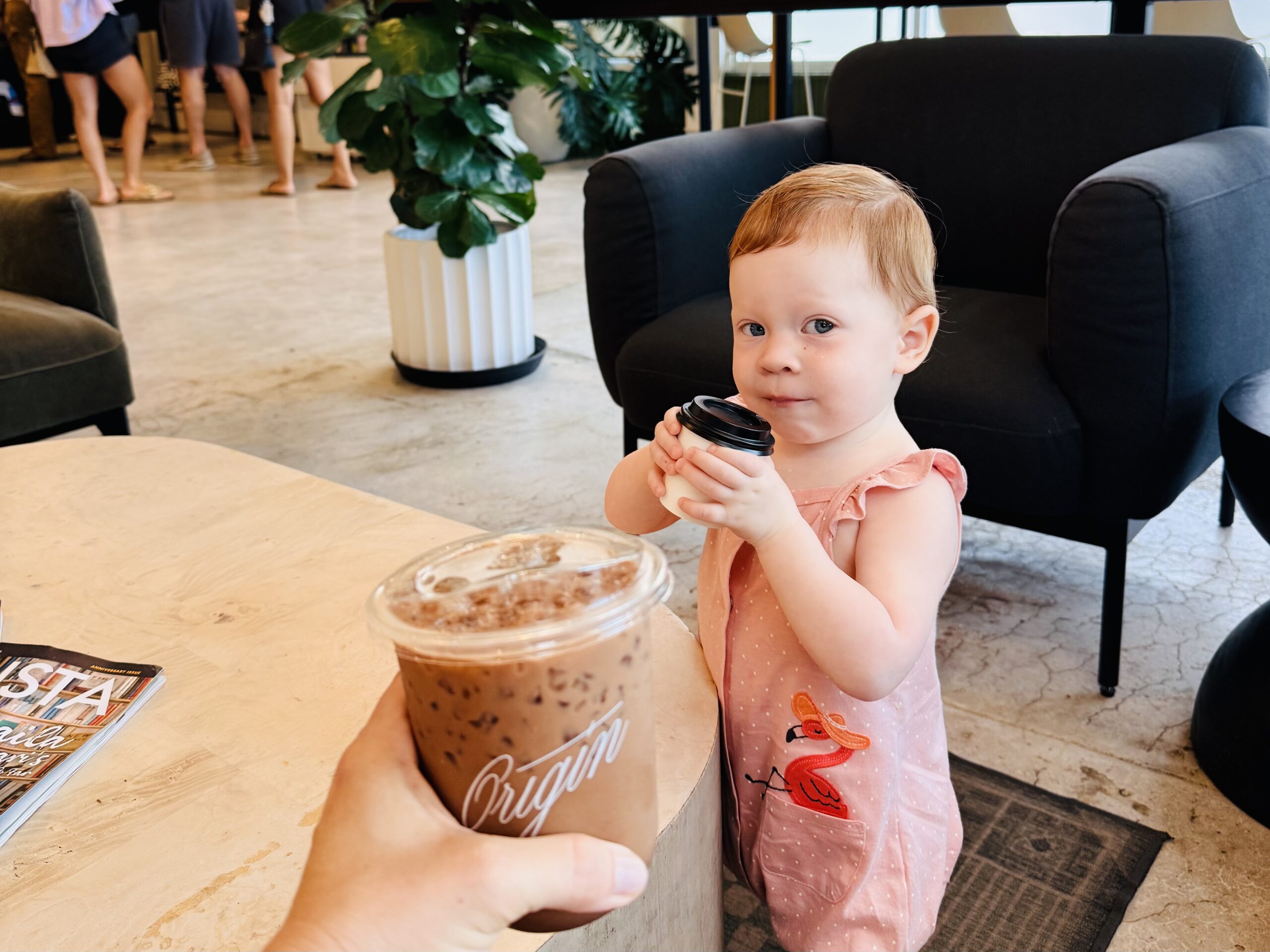 Baby drinking milk while mom drinks coffee
