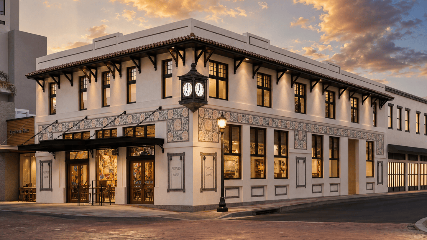 A historic two-story building with decorative tiles, large windows, a corner clock, and warm lighting at dusk beneath a colorful sky.