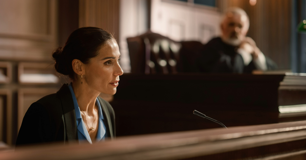 Woman testifying in court as an expert witness during litigation with the judge in the background.