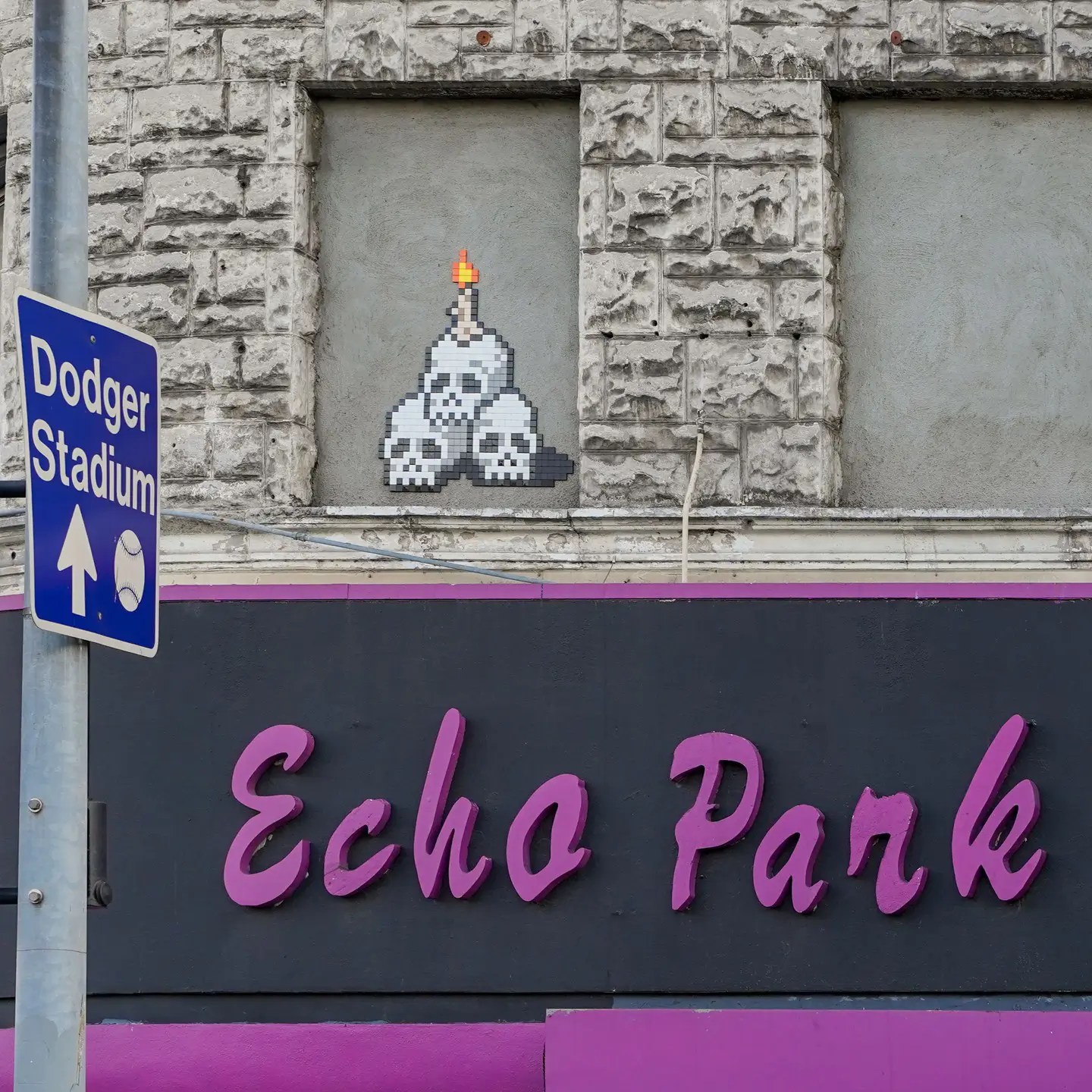 A photo of an artwork by Space Invader shows tiles representing a stack of three skulls with a candle on top