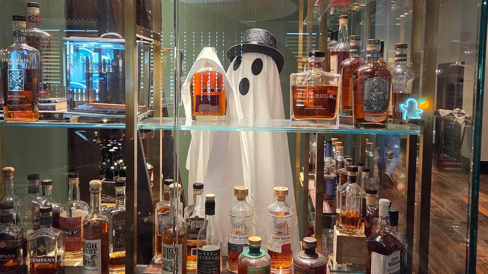 person in a white ghost costume and a black top hat standing behind the whiskey keep at 1799 Kitchen and Bar Room