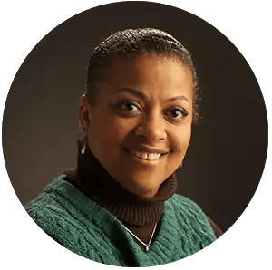 Hearing specialist smiling, wearing green sweater, at Hart Hearing & Balance Centers.