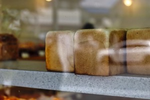 ガラス越しに写ってるパン屋の食パンの画像
