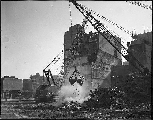 A black-and-white historic photo of a crane demolishing a building, featured in the Hawthorne company timeline.