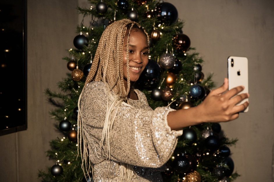 woman in white long sleeve top standing beside a christmas tree