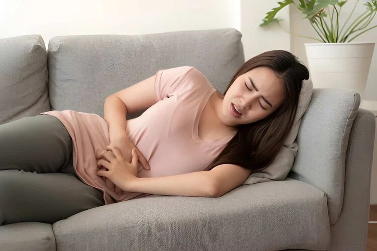 woman with stomach pain sleeping on a couch