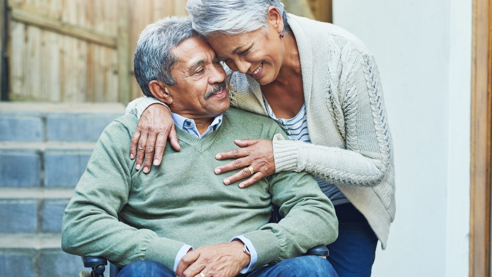Support, wheelchair and senior couple hug with care, smile and love by elderly happy people in retirement. Old man, rehabilitation and person with disability and woman helping in empathy in marriage.