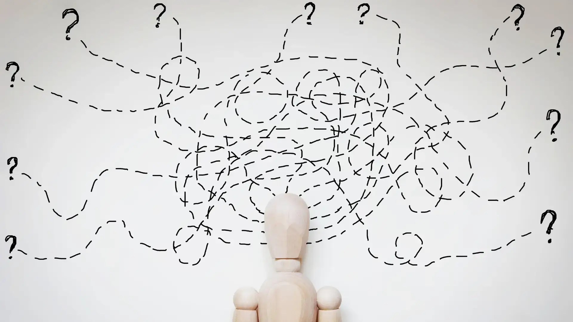 Image of a wooden mannequin with lines going from its head leading to question marks.