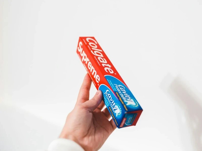 person holding colgate toothpaste box