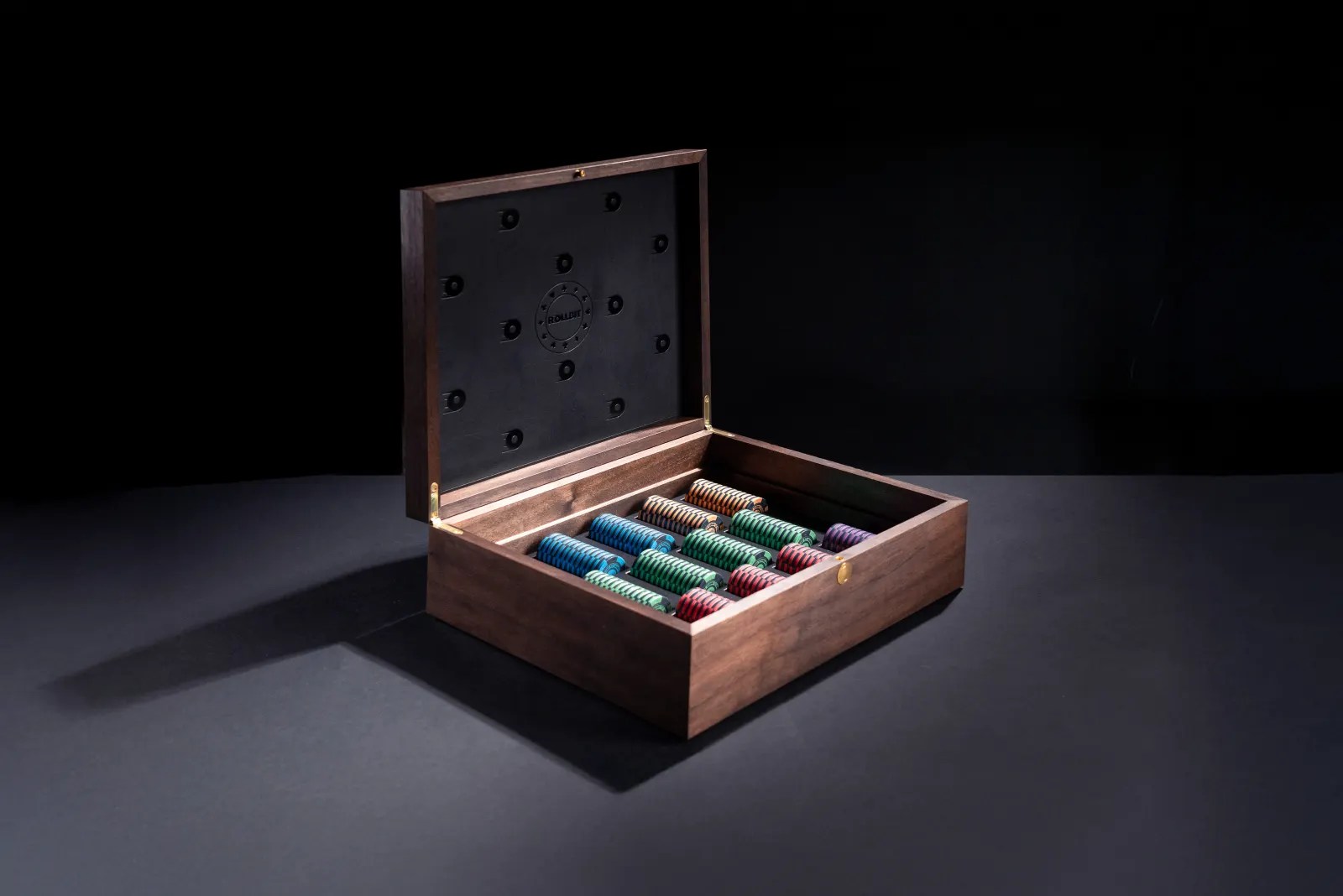 The walnut poker case open on a dark backdrop, rows of coloured chips in its fitted tray