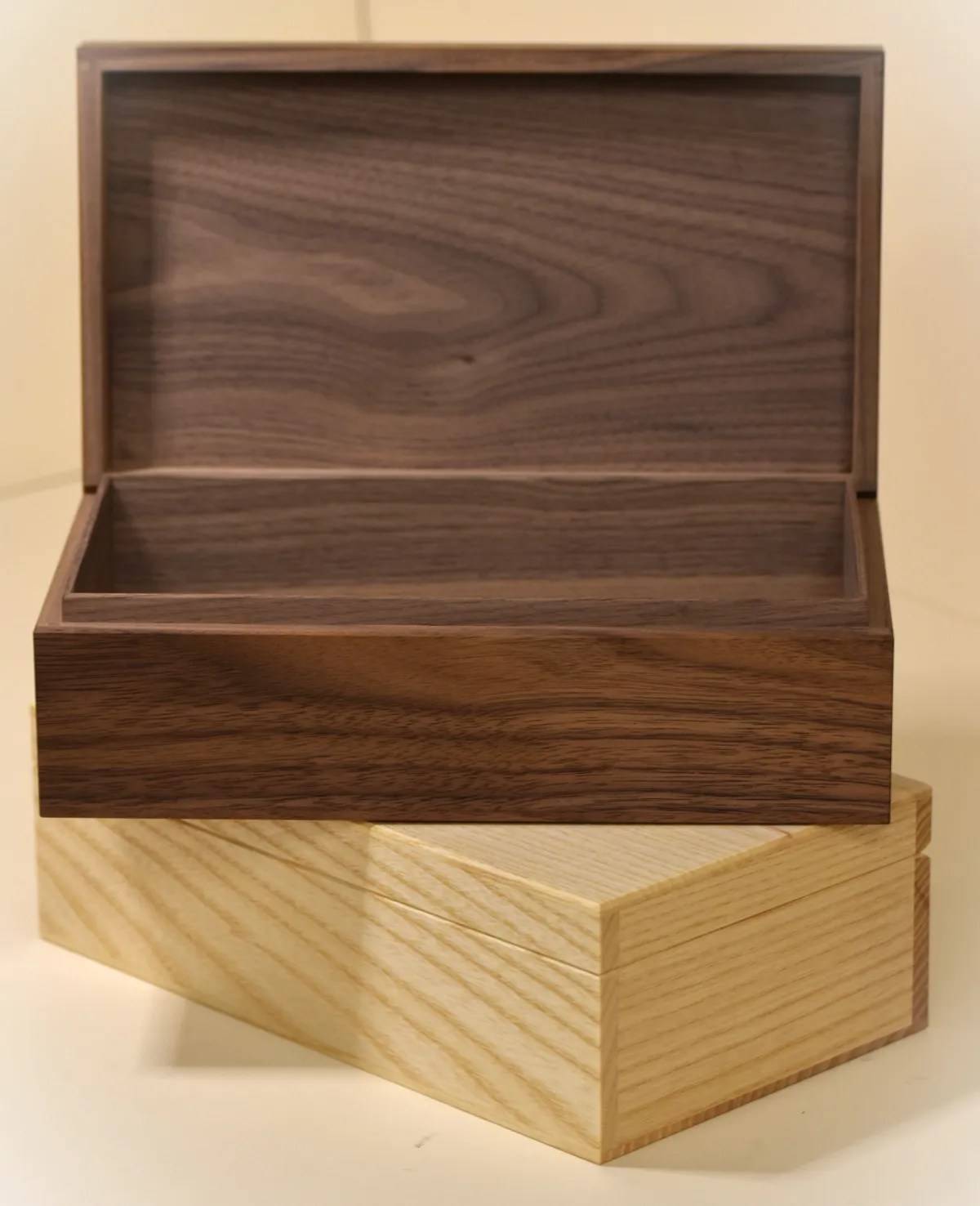 A walnut box with its lid open, stacked on a closed ash box