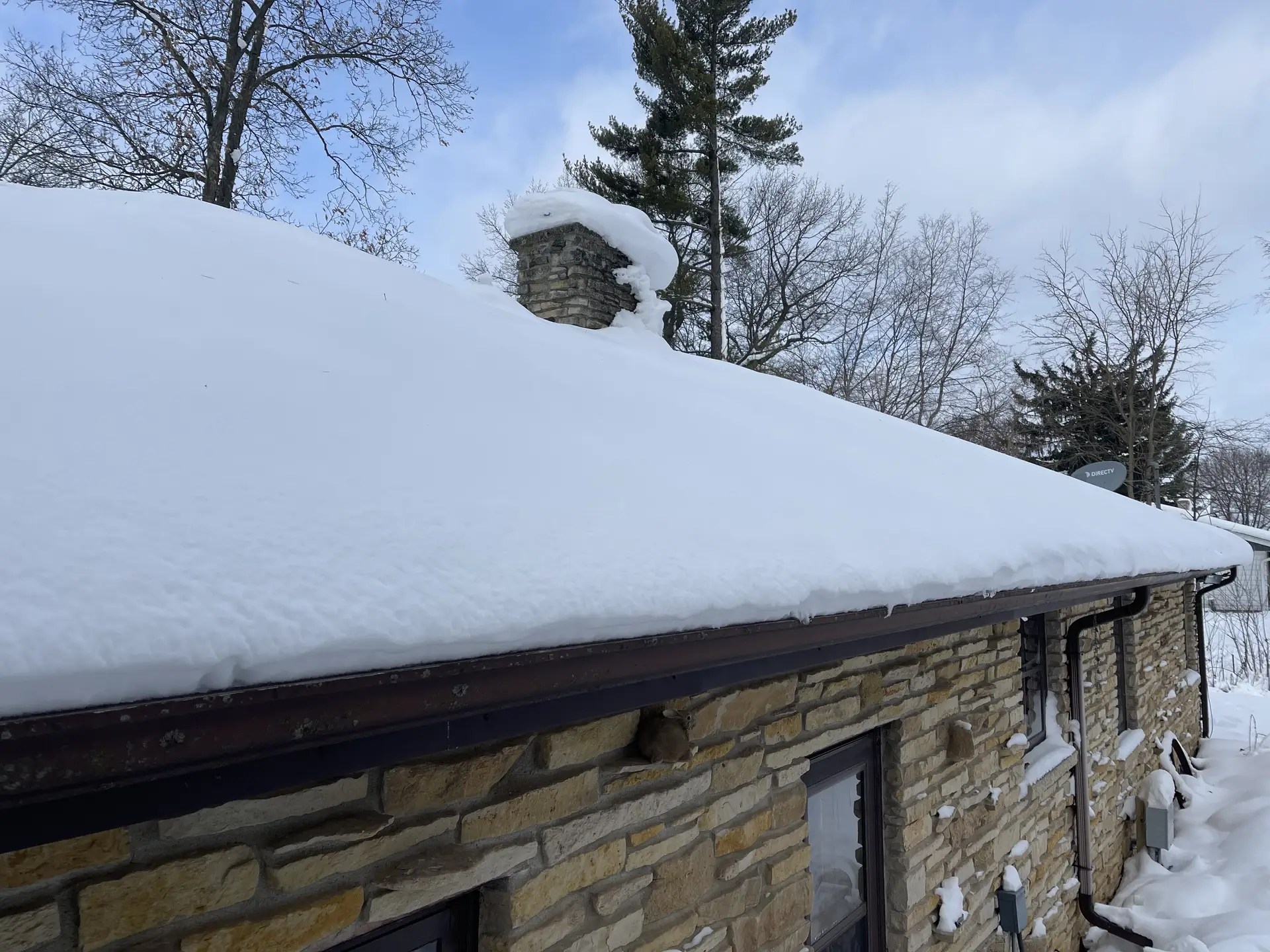 Roof Raking a snow covered house.