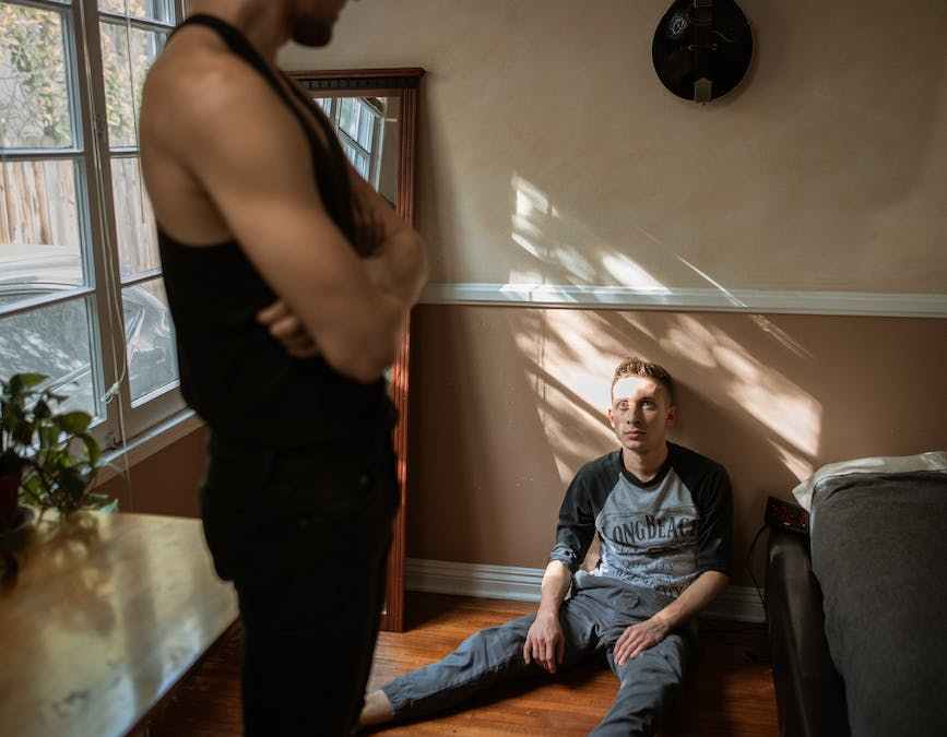 man in black tank top and pants looking at a boy sitting