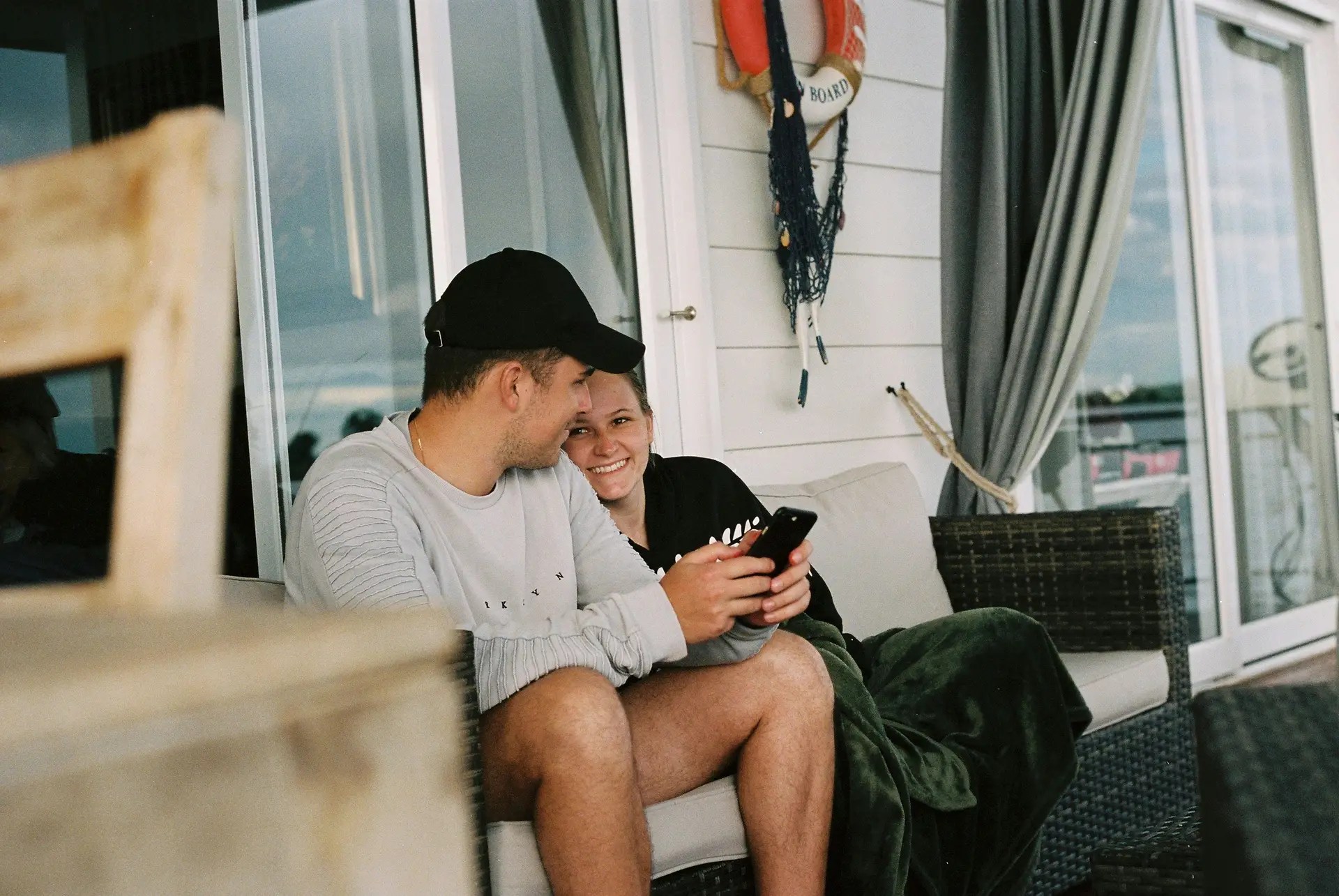 Happy couple sitting together on a porch looking at a phone app