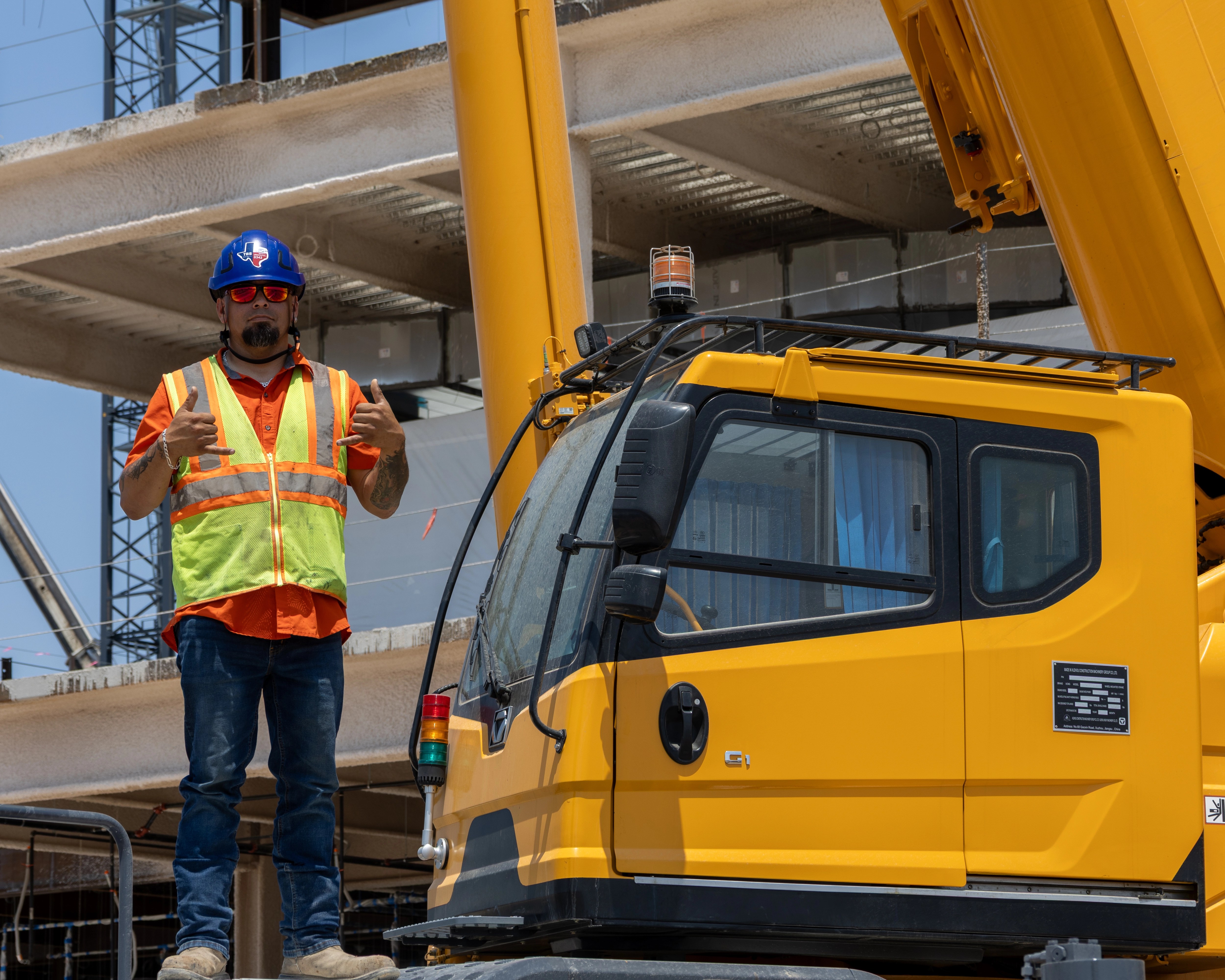 Fernando, crane operator for Torre Crane, standing on the deck of an XCMG XCR130 after successfully aiding in building a hospital in San Antonio, Texas