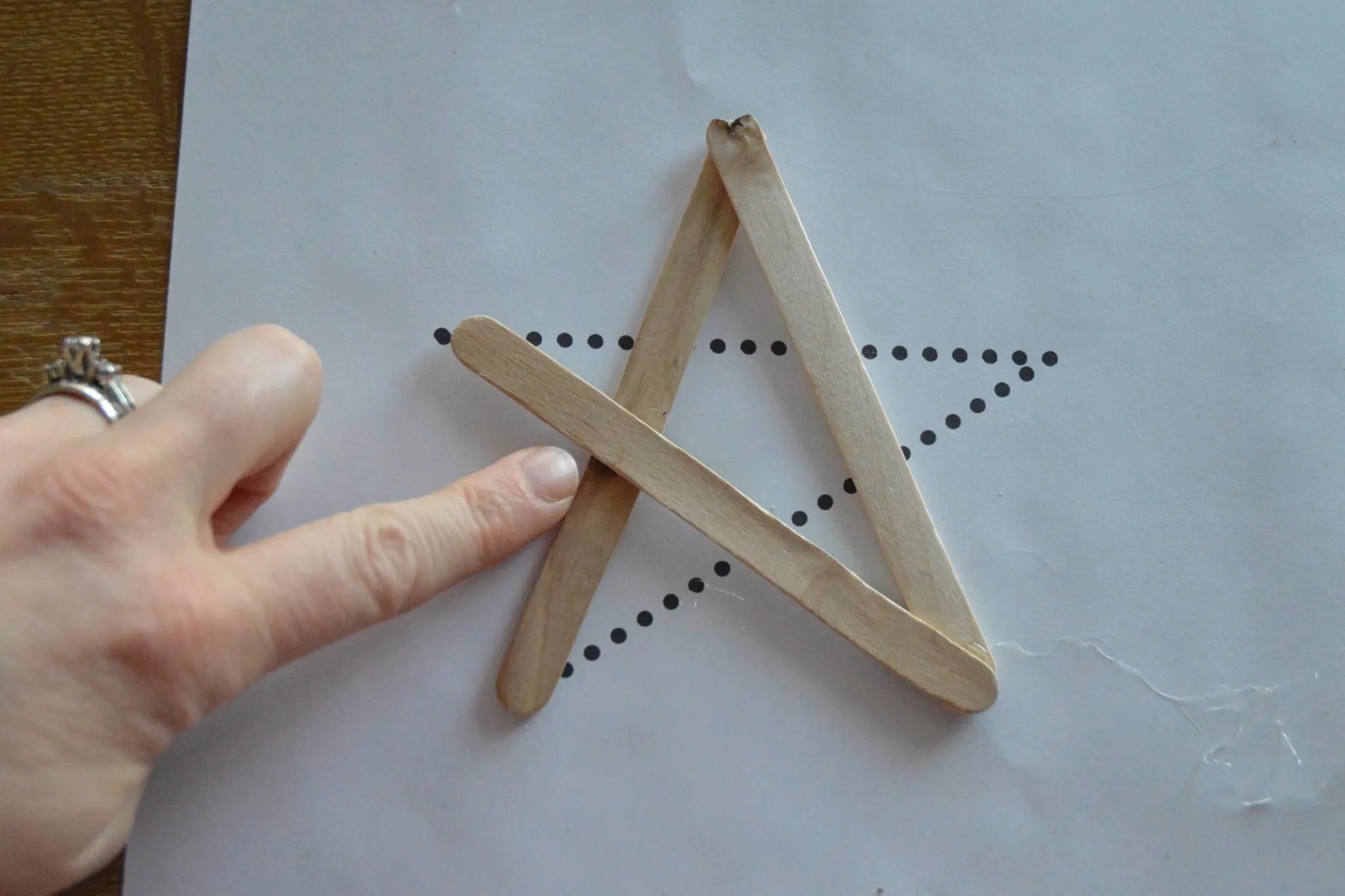This shows where to place an extra glue dot to provide more stability to the star. The glue dot should be placed where the first and third popsicle sticks cross.