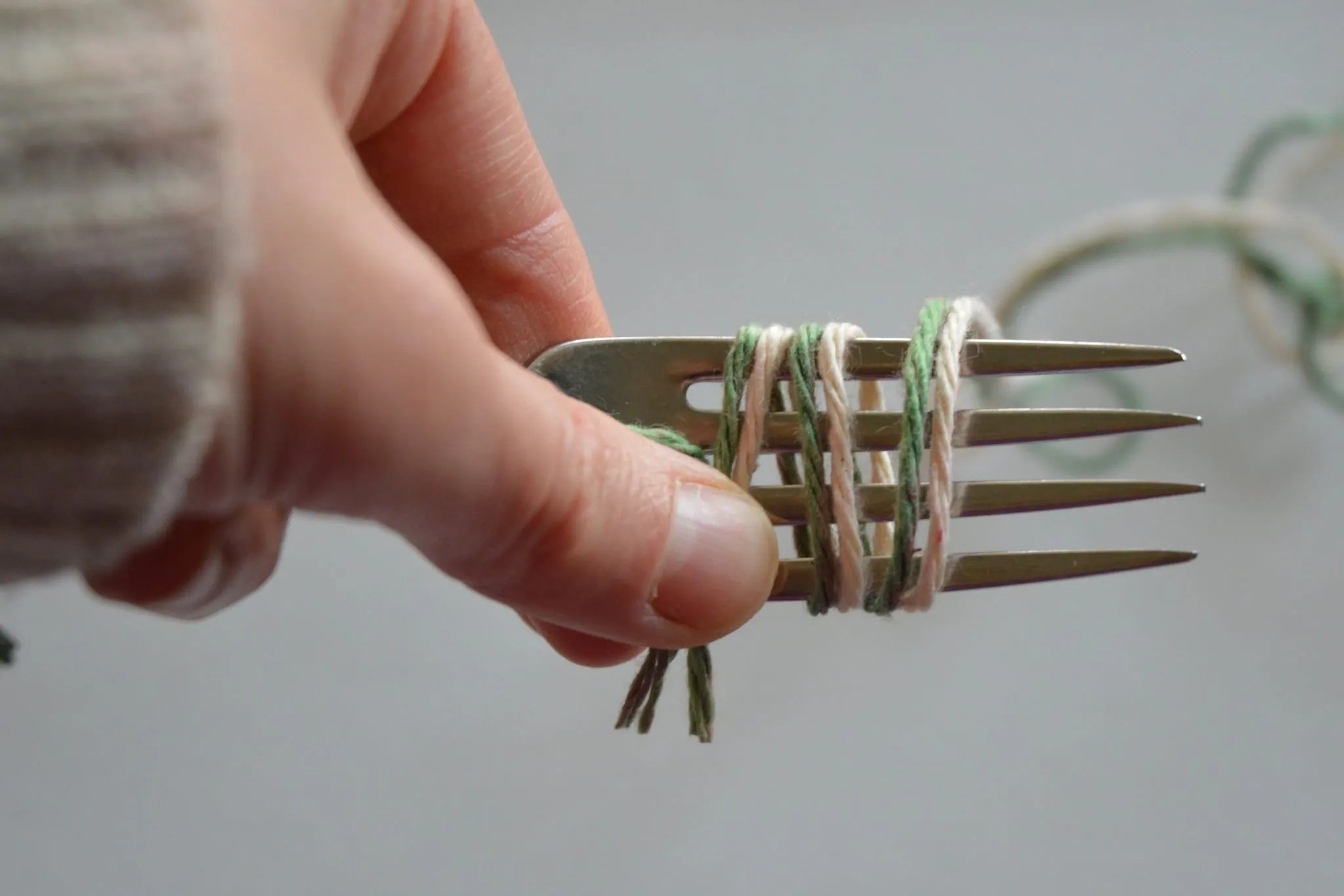 Hold the fork and yarn in your left yarn. Wrap the yarn around the fork to create the pom pom.