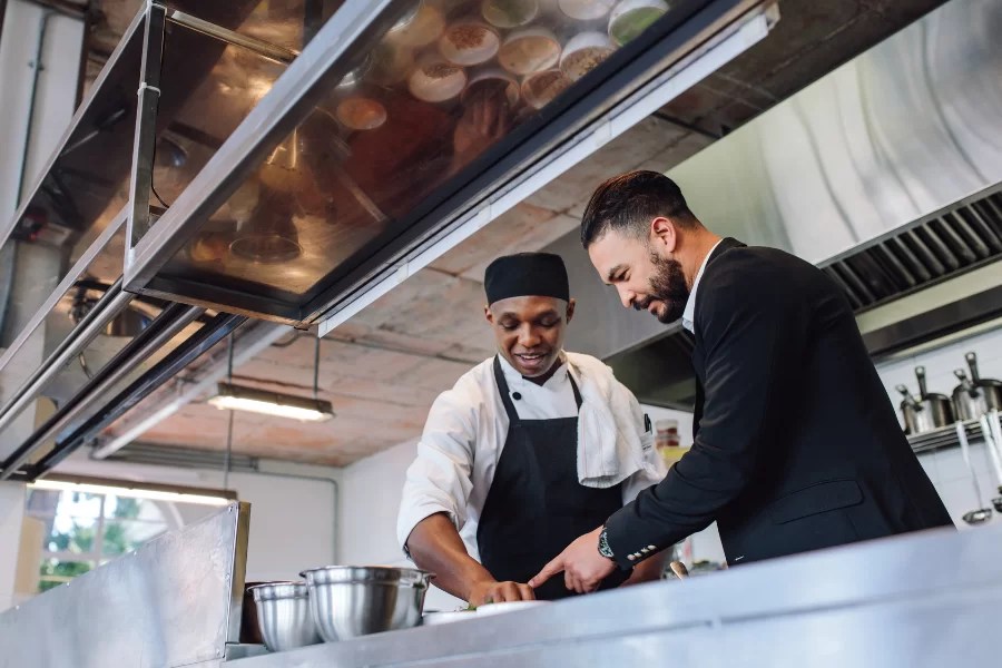 A restaurant manager is giving direction to a cook.