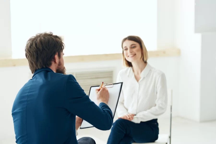 person with clipboard asking questions to another person
