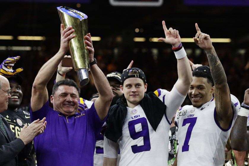 Louisiana State coach Ed Orgeron holds the trophy beside quarterback Joe Burrow, center, and safety Grant Delpit after beating Clemson in the College Football Playoff championship game in New Orleans.