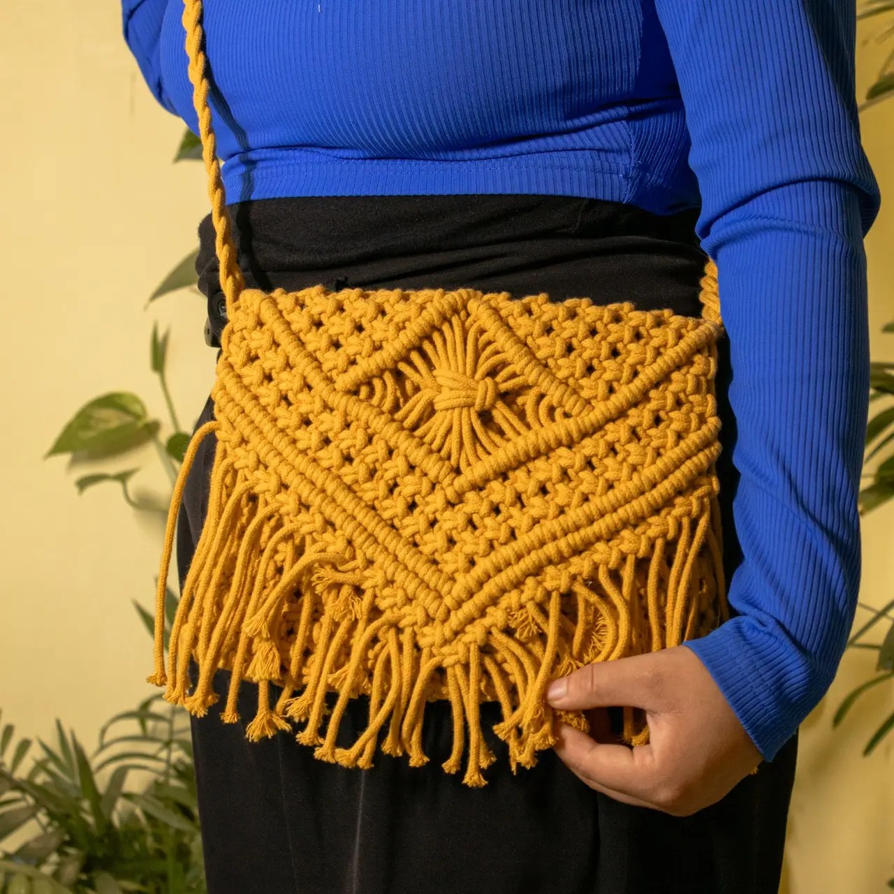 Golden handmade macrame crossbody bag with fringe detail, worn by woman in blue ribbed top — eco-friendly, minimalist, perfect for daily use and travel