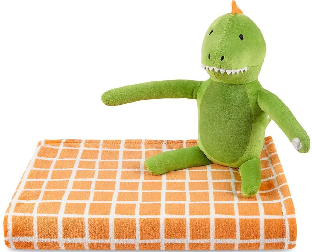 Plush dinosaur sitting on an orange checked blanket