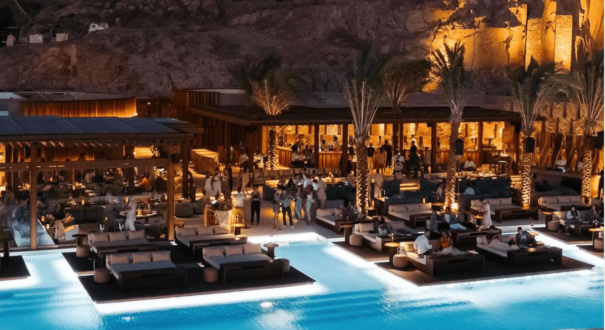 Al fresco sunset dinner setting at Zuma Mykonos with iroko wood pergolas and views of the Old Port.