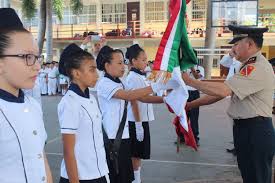Imagen de niños en una escolta, uno de los integrantes trae lentes y otro está cargando {a bandera