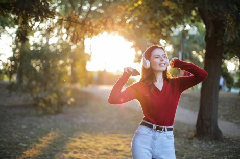 woman in red long sleeve shirt and blue denim jeans standing on brown field