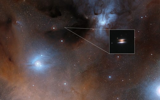 The young star 2MASS J16281370-2431391 lies in the spectacular Rho Ophiuchi star formation region, about 400 light-years from Earth. It is surrounded by a disc of gas and dust — such discs are called protoplanetary discs as they are the early stages in the creation of planetary systems. This particular disc is seen nearly edge-on, and its appearance in visible light pictures has led to its being nicknamed the Flying Saucer. The main image shows part of the Rho Ophiuchi region and a much enlarged close-up infrared view of the Flying Saucer from the NASA/ESA Hubble Space Telescope is shown as an insert.