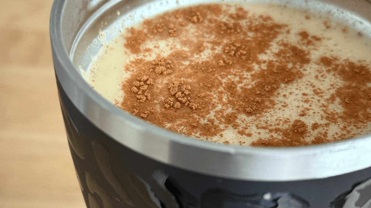 Image of coffee cup with coffee and cinnamon on top.