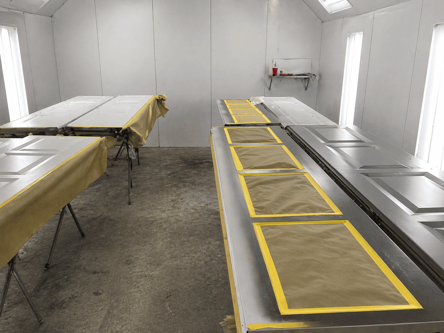 Two long garage door panels in a paint booth masked for spray painting