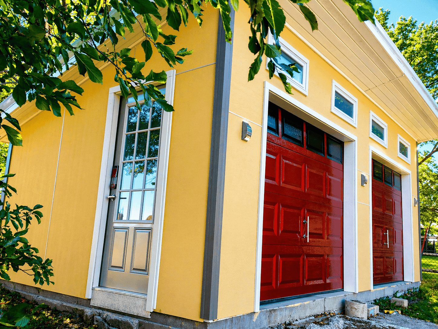 Finished shed with yellow walls red garage doors and gray side entry door