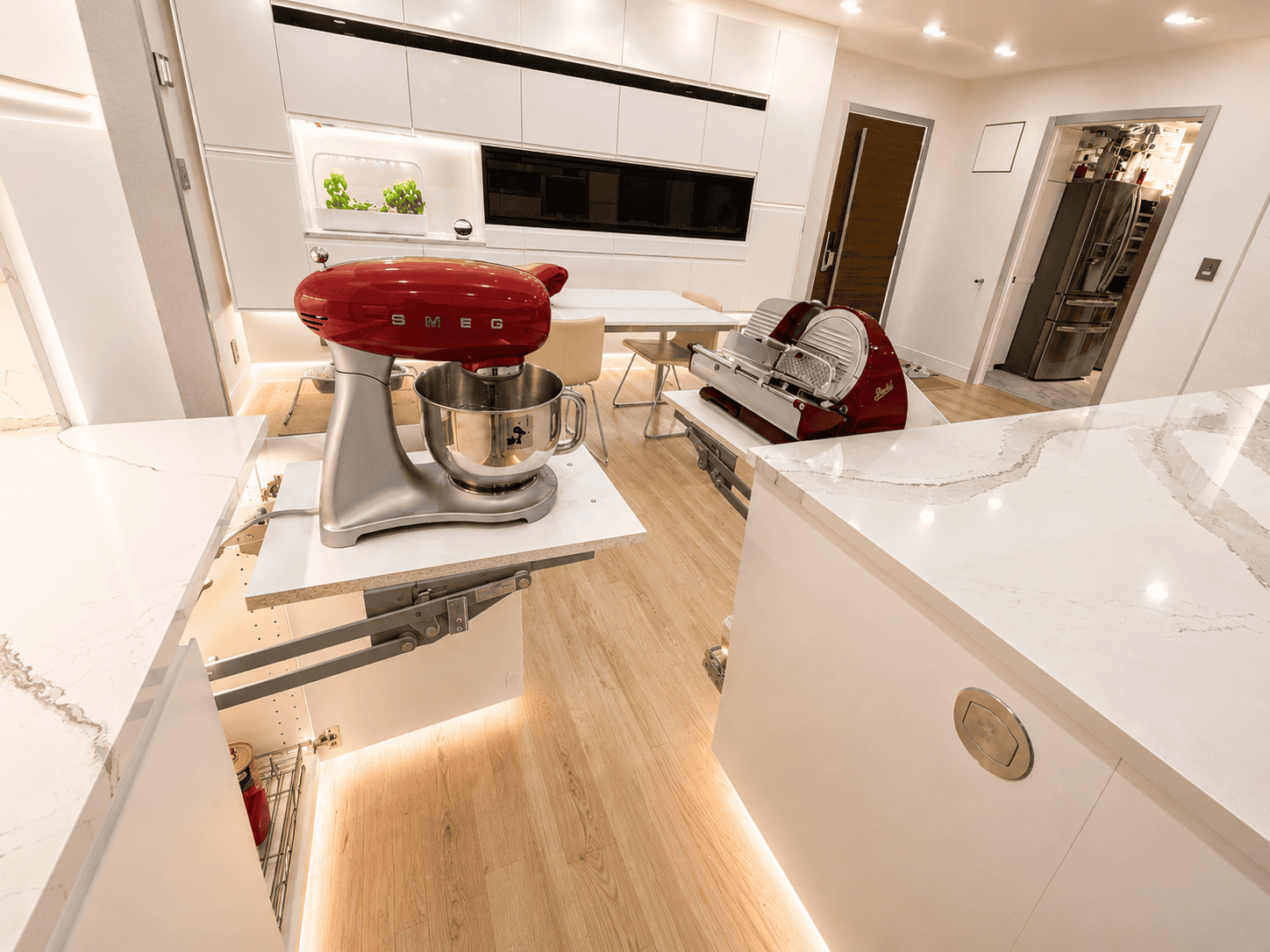 A modern kitchen featuring a red SMEG stand mixer on a pull-out drawer, with a stylish countertop and ambient lighting.