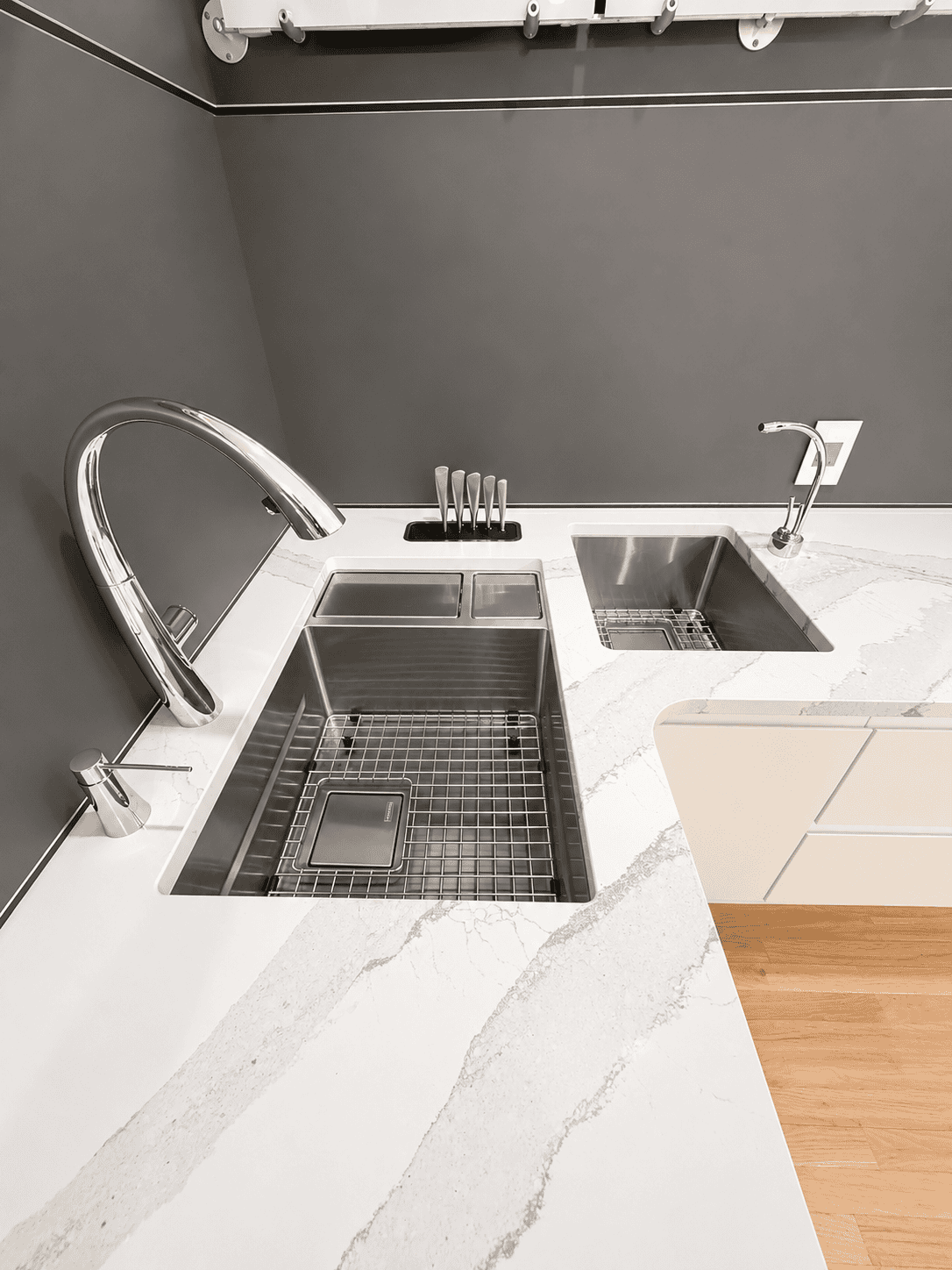 Modern kitchen sink with stainless steel basins, a sleek faucet, and a white quartz countertop featuring a subtle gray vein design.