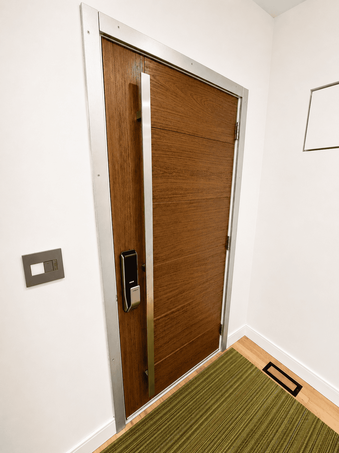 Wooden door with metal frame and electronic lock in a modern interior.