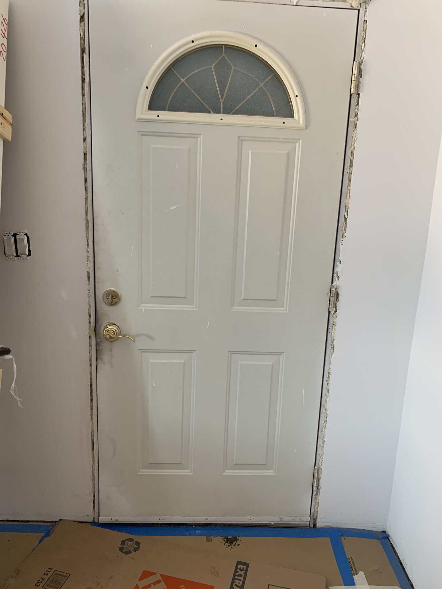 White interior door with semi-circular glass window and brass handle.