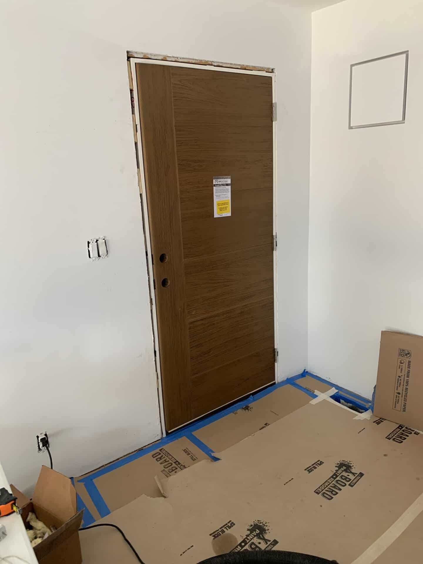 New wooden interior door being installed in a room under renovation.