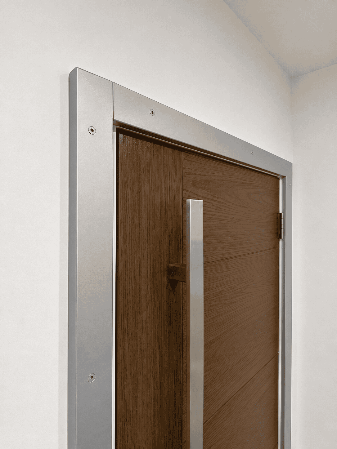 Close-up of silver metallic door trim with exposed hex screws and a long pull bar.