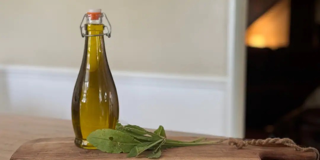 flip top bottle of plantain infused sunflower oil with plantain leaves next to it.