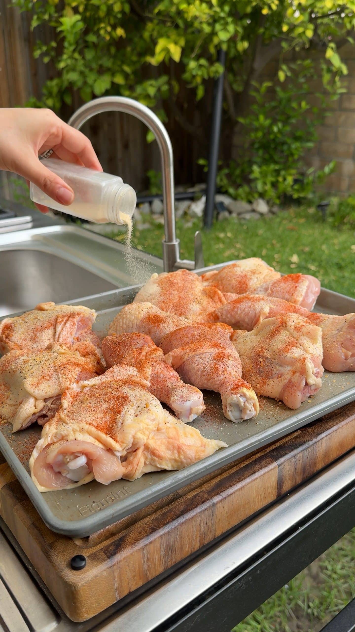 Smoked paprika being sprinkled over chicken pieces.