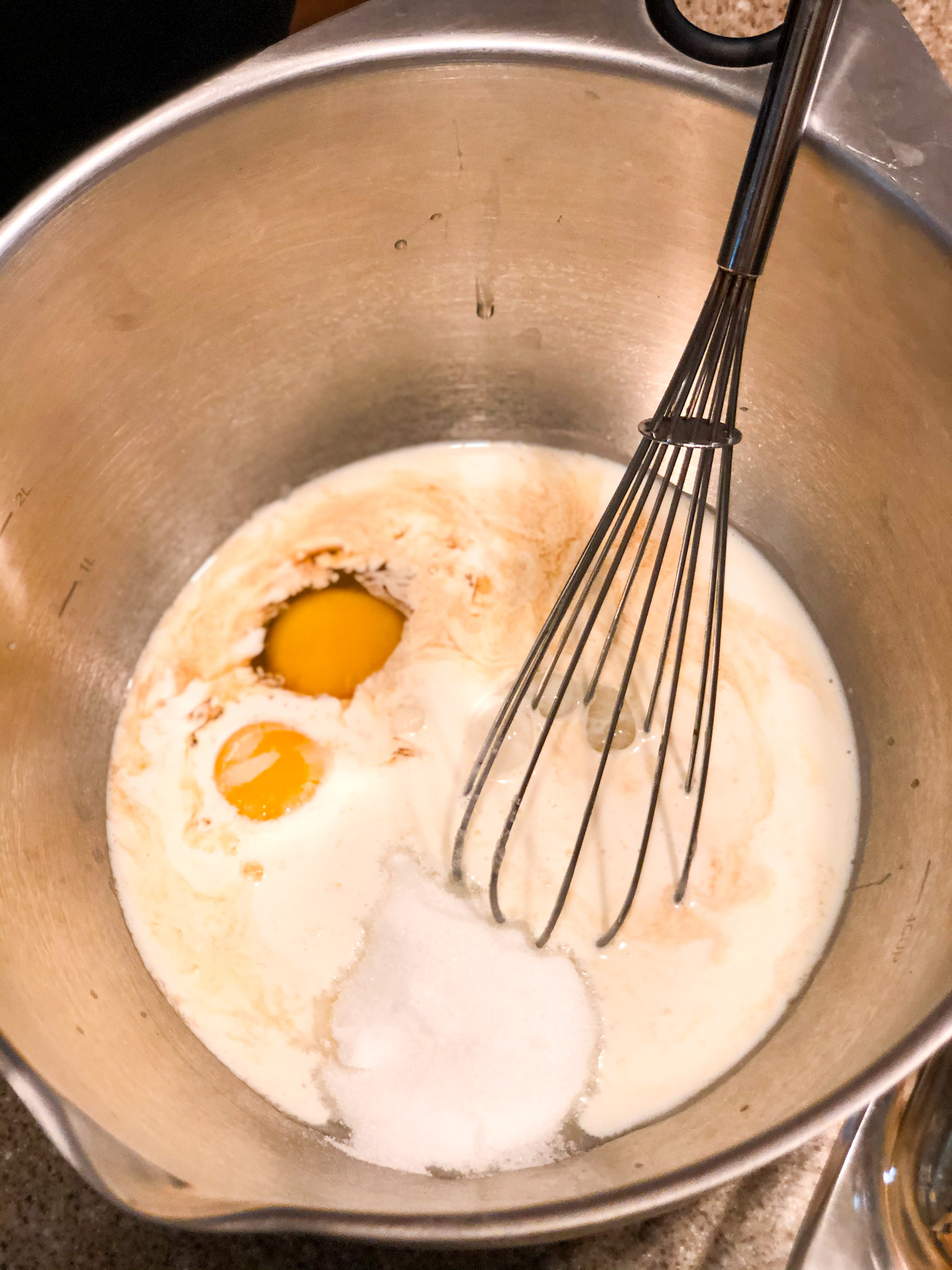 custard mix ingredients in a stainless steel bowl with whisk