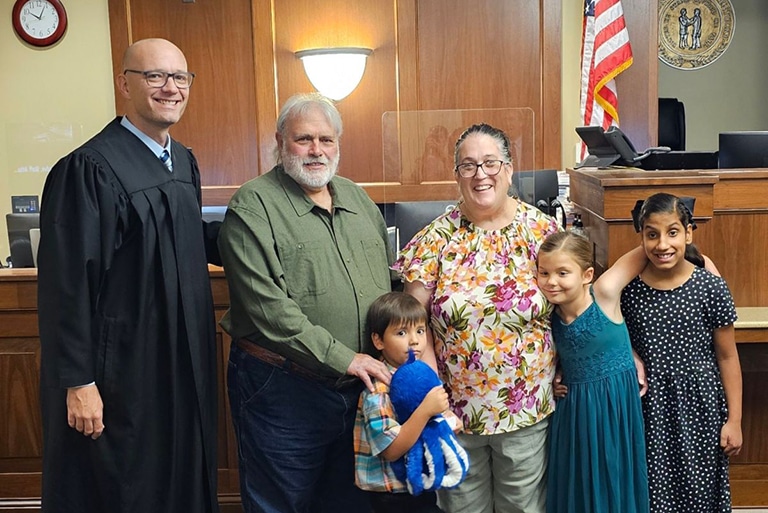 photo of foster family with judge at adoption ceremony