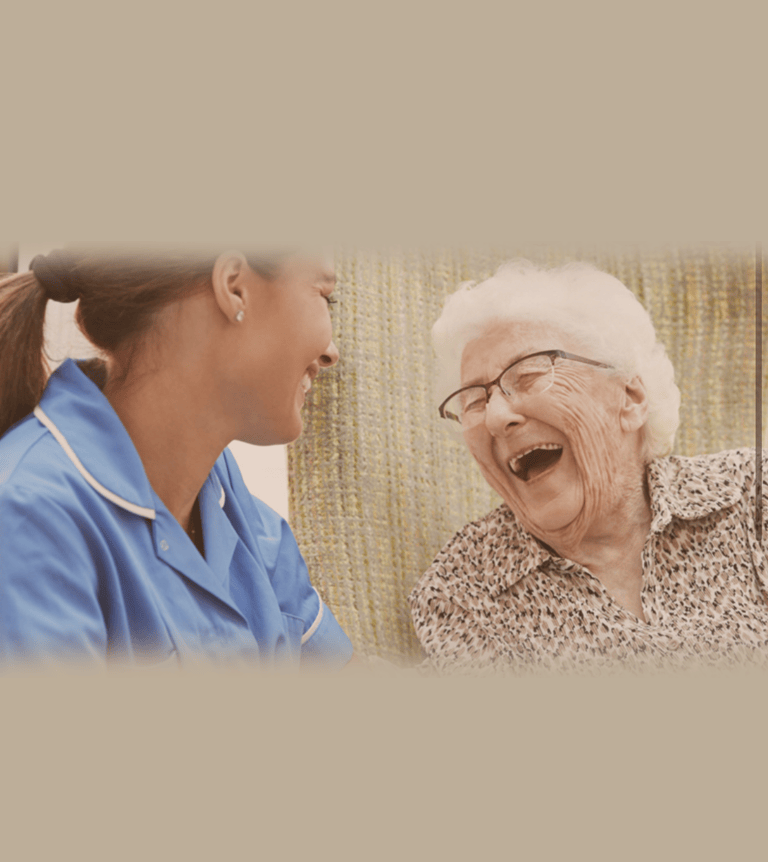 An older woman laughing with a caregiver