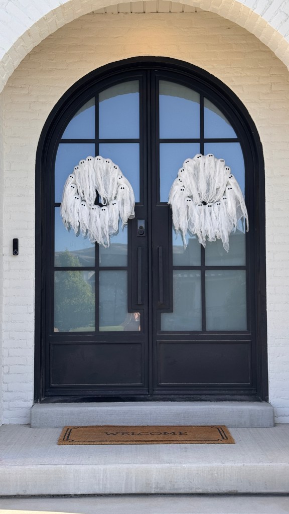 DIY light-up ghost wreath made with clear ornaments and cheesecloth on a front door