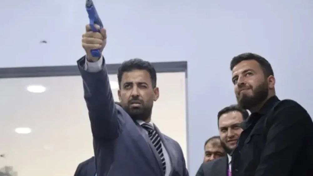 وزير الصحة السوري مصعب العلي خلال تجربة الرماية في جناح وزارة الداخلية بمعرض دمشق الدولي – مواقع التواصل.