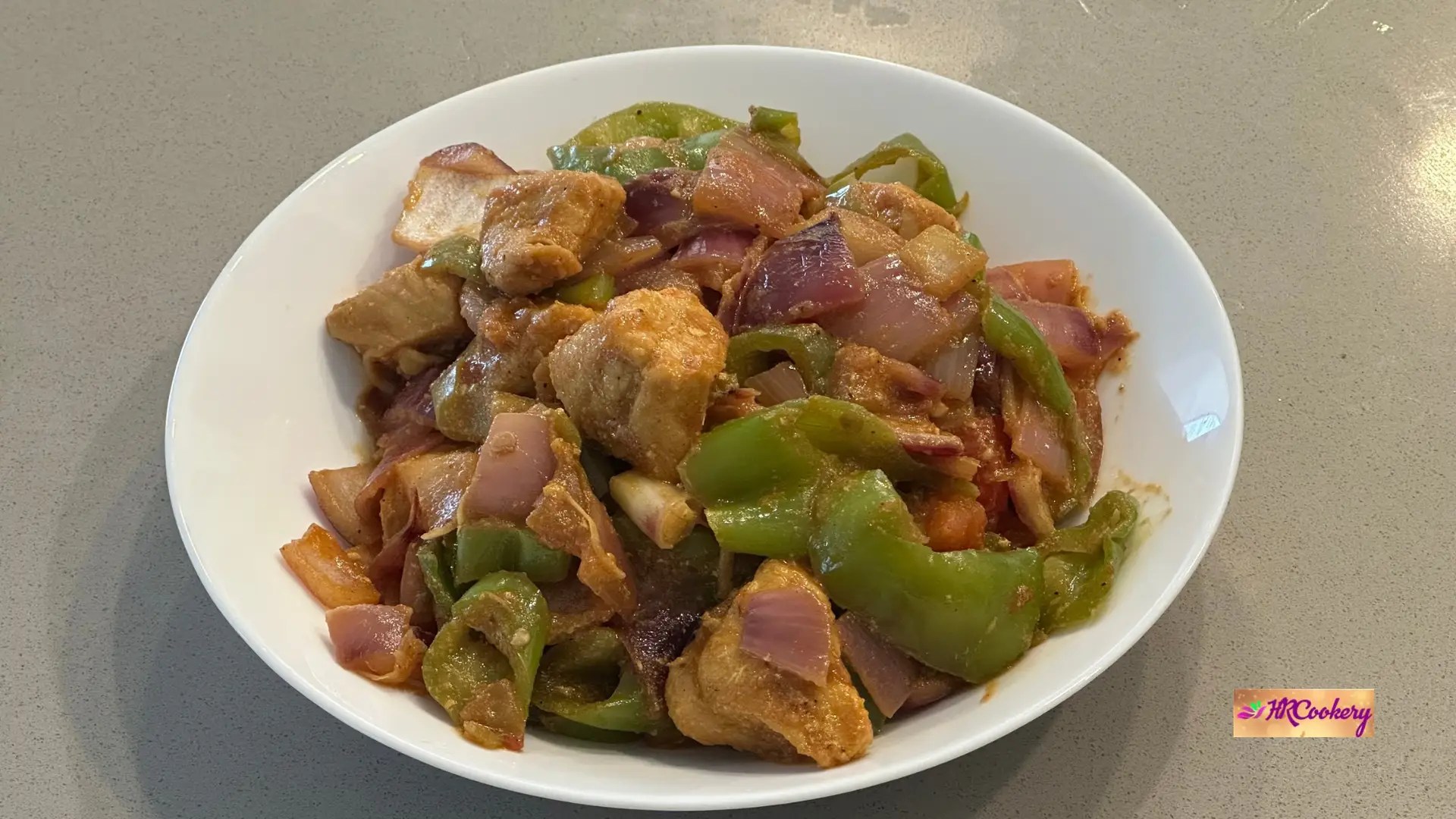 Sri Lankan deviled chili chicken stir-fry with chicken breast, green bell peppers, and red onions in a spicy glossy sauce.